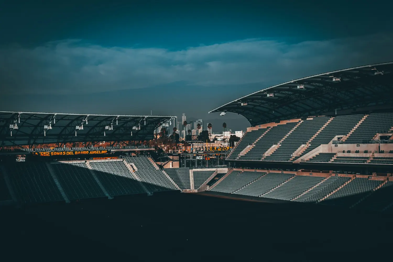 Gradas de un estadio al atardecer con la ciudad al fondo