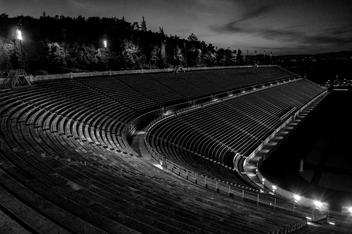 Gradas vacías de un estadio al anochecer, en blanco y negro